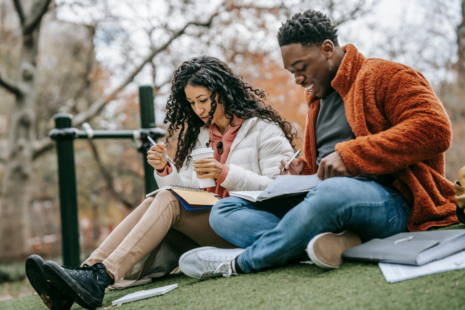 Two students studying together outdoors on a park bench.