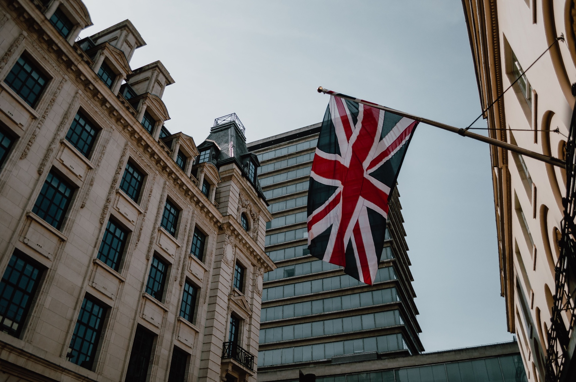 Union Jack flag flying between historic and modern buildings in London.